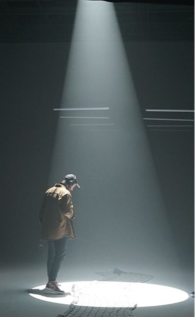 Figure standing in a spotlight in the studio
